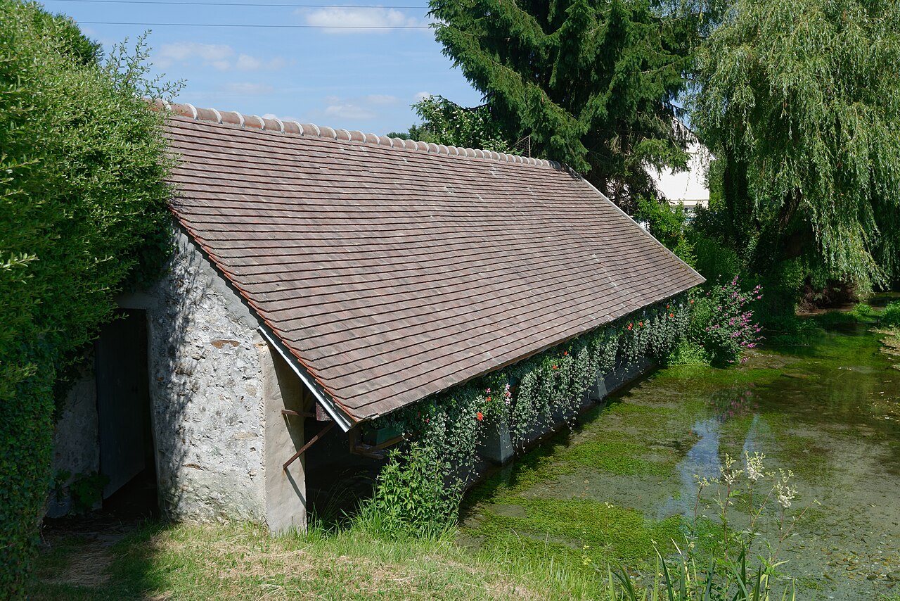 Oud overdekt washuis of lavoir aan het water, met pannendak en stenen muren